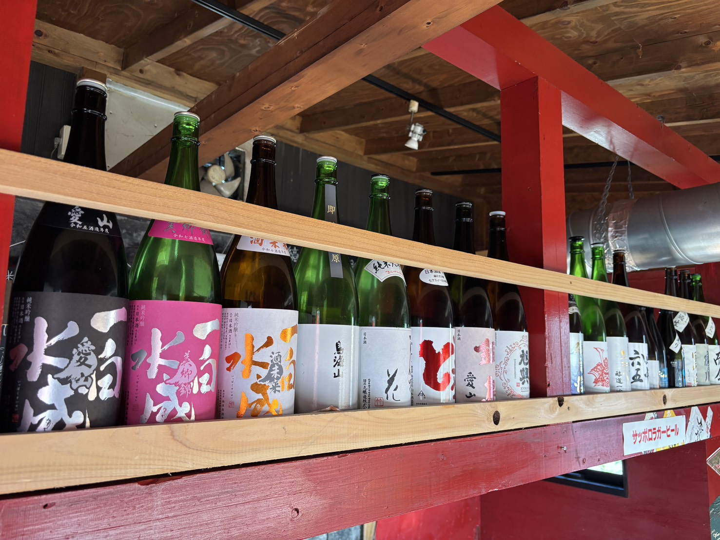 赤い梁の棚に並ぶ日本酒の瓶