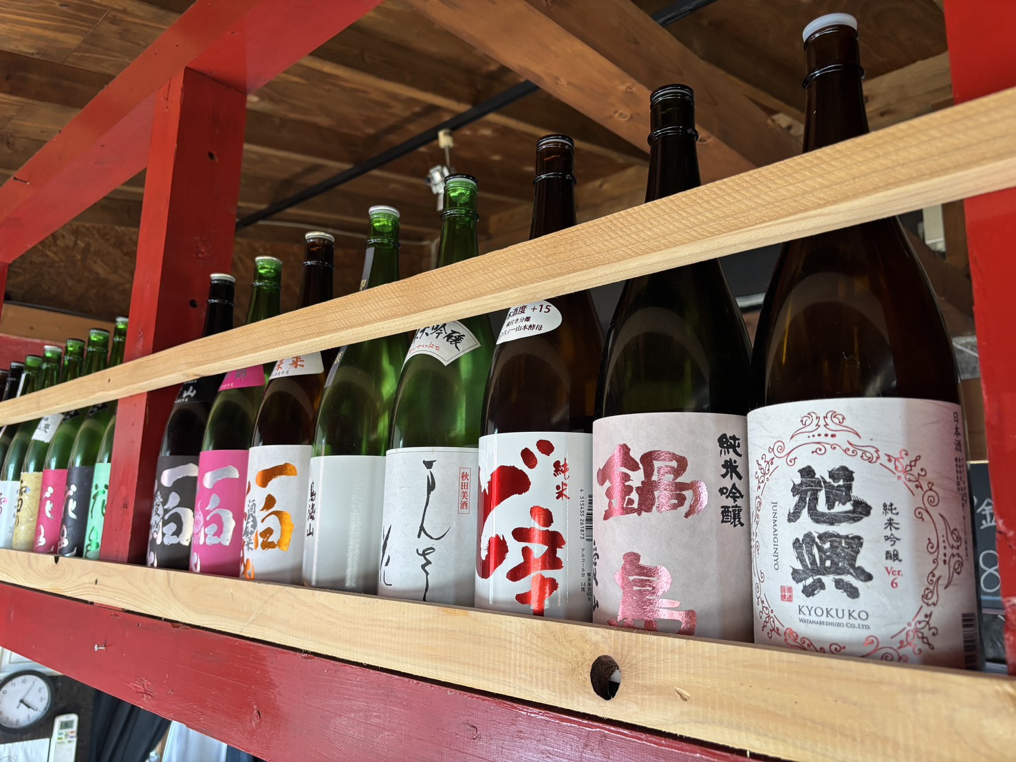 赤い梁の棚に並ぶ日本酒の瓶を近くから撮影した写真